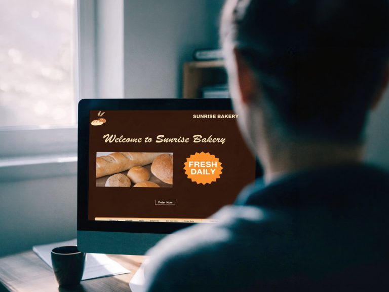 A person looking at an outdated bakery website with the full screen visible on a desktop monitor.